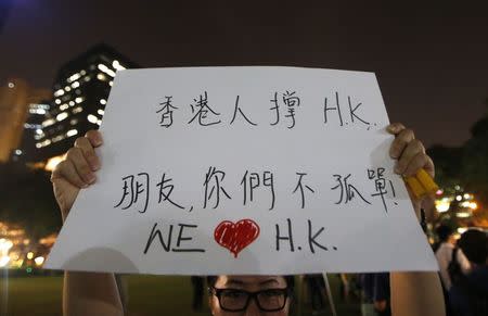 A woman holds up a placard that reads, "People of Hong Kong support Hong Kong. Friends, you are not alone" during a candlelight vigil in solidarity with protesters of the "Occupy Central" movement in Hong Kong, at the Hong Lim Park Speakers' Corner in Singapore October 1, 2014. REUTERS/Edgar Su
