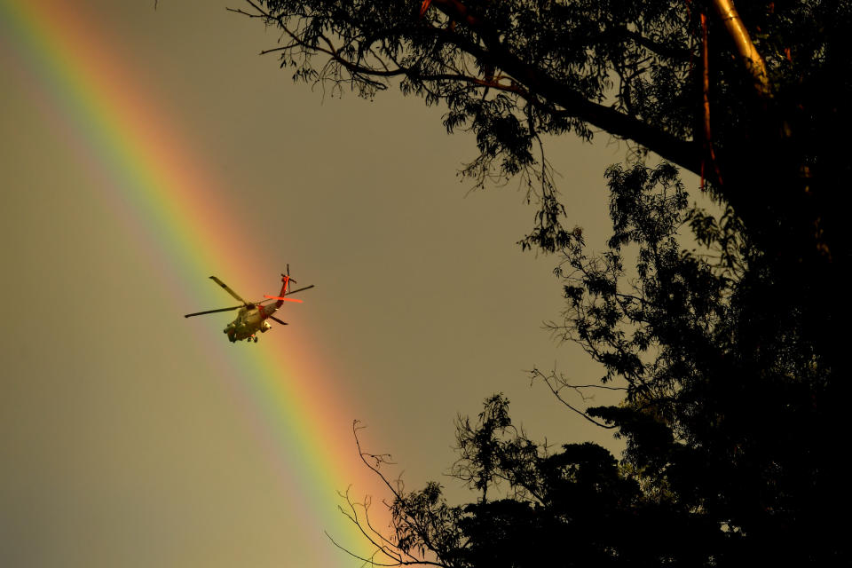 A Coast Guard helicopter heads to Montecito as a rainbow appears.