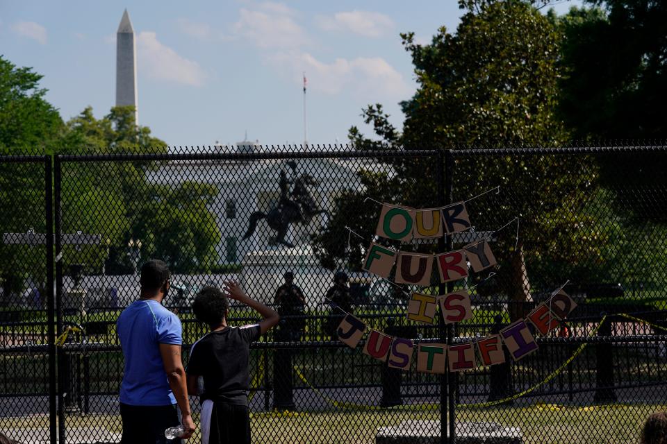 With the White House in the background, people stand against a fence Thursday, June 4, 2020, in Washington as demonstrators protest over the death of George Floyd, a black man who was in police custody in Minneapolis.