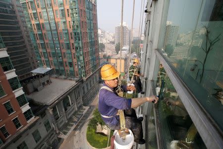 FILE PHOTO: Workers clean the windows of an apartment block in Beijing, China, June 27, 2017. REUTERS/Jason Lee/File Photo