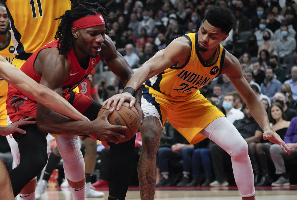 Toronto Raptors forward Precious Achiuwa (5) battles for the ball against Indiana Pacers guard Jeremy Lamb (26) during the first half of an NBA basketball game, Wednesday, Oct. 27, 2021 in Toronto. (Nathan Denette/The Canadian Press via AP)