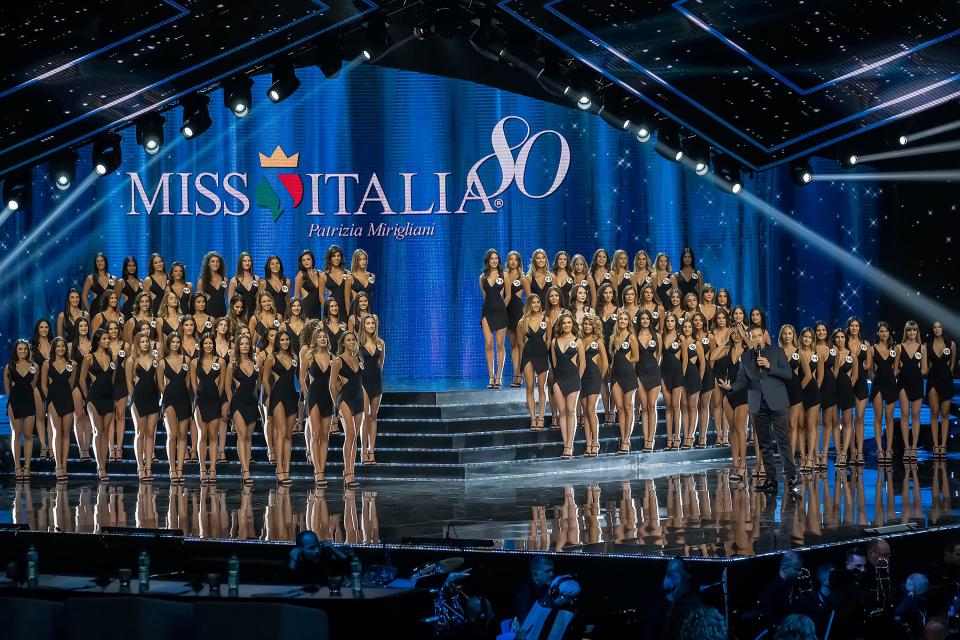The participants of the Miss Italia 2019 competition standing on a stage in rows.