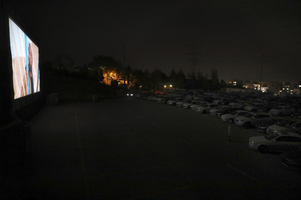 People sit in their cars watching a movie at a new drive-in cinema on a car parking area of the Milad telecommunications tower, as regular theaters are closed due to the coronavirus outbreak, Friday, May 1, 2020. Iran is the region's epicenter of the COVID-19 pandemic. (AP Photo/Vahid Salemi)