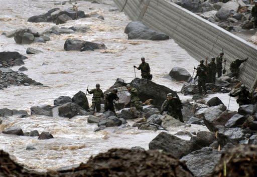 Japan's Self Defense Force members search for missing residents in the rain, in Takeda, Oita Prefecture, Japan, Friday, July 13, 2012. Heavy rains hit southern Japan, triggering flashfloods, mudslides and destroying dozens of homes. (AP Photo/Kyodo News)