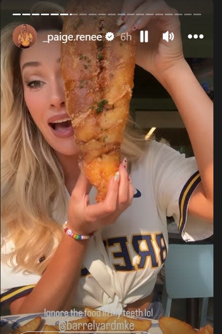 Golf social media influencer Paige Spiranac shows how big the beer-battered walleye is at J. Leinenkugel’s Barrel Yard inside American Family Field on Friday, June 16, 2023. Spiranac was at the Brewers game for Golf Night.