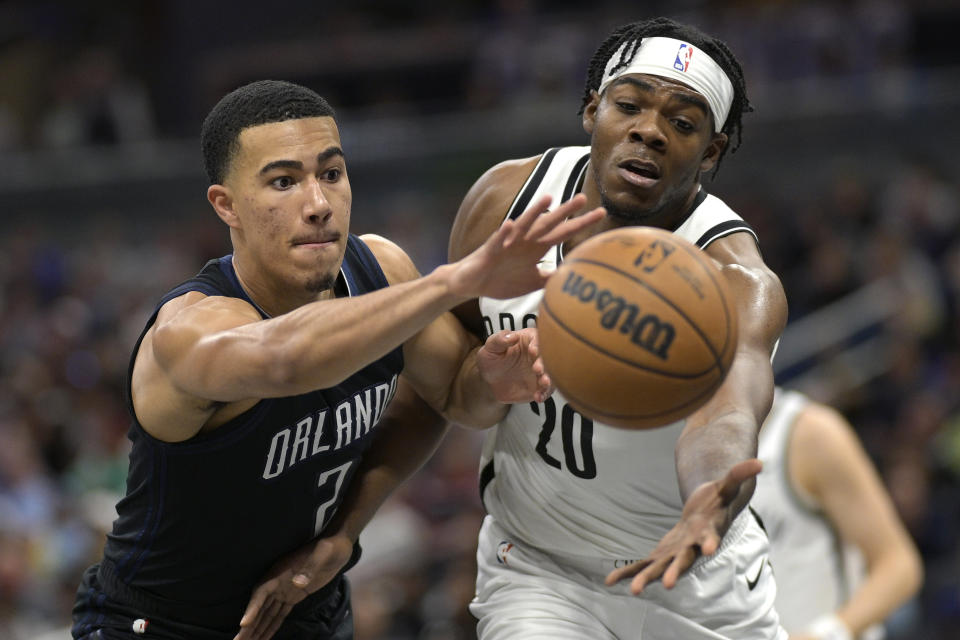 Orlando Magic guard Caleb Houstan (2) and Brooklyn Nets center Day'Ron Sharpe (20) compete for a rebound during the first half of an NBA basketball game, Sunday, March 26, 2023, in Orlando, Fla. (AP Photo/Phelan M. Ebenhack)