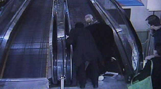 A still image taken from security video, showing horrified onlookers helping the couple at the top of the travelator.