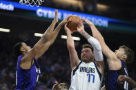 Dallas Mavericks guard Luka Doncic (77) is defended by Sacramento Kings forward Domantas Sabonis,right, and forward Keegan Murray, left, as he shoots in the first half of an NBA basketball game in Sacramento, Calif., Tuesday, March 26, 2024. (AP Photo/José Luis Villegas)