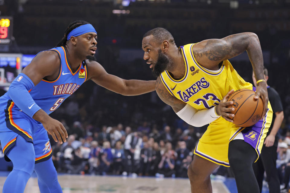 Los Angeles Lakers forward LeBron James, right, holds the ball as Oklahoma City Thunder guard Luguentz Dort (5) defends during the first half of an NBA basketball game, Thursday, Nov. 30, 2023, in Oklahoma City. (AP Photo/Nate Billings)