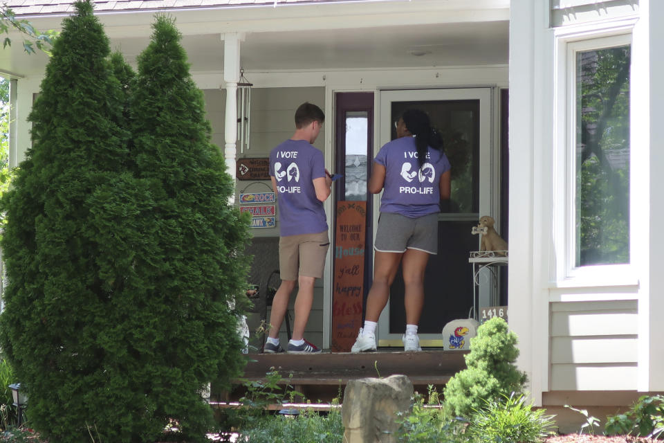FILE - Ben Kennedy, left, and Alyssa Winters, left, wait at a door to speak with prospective voters about a proposed amendment to the Kansas Constitution that would allow legislators to further restrict or ban abortion, Friday, July 8, 2022, in Olathe, Kan. They are among about 300 college students brought into Kansas by the Susan B. Anthony Pro-Life America group, which backs the measure. (AP Photo/John Hanna, File)