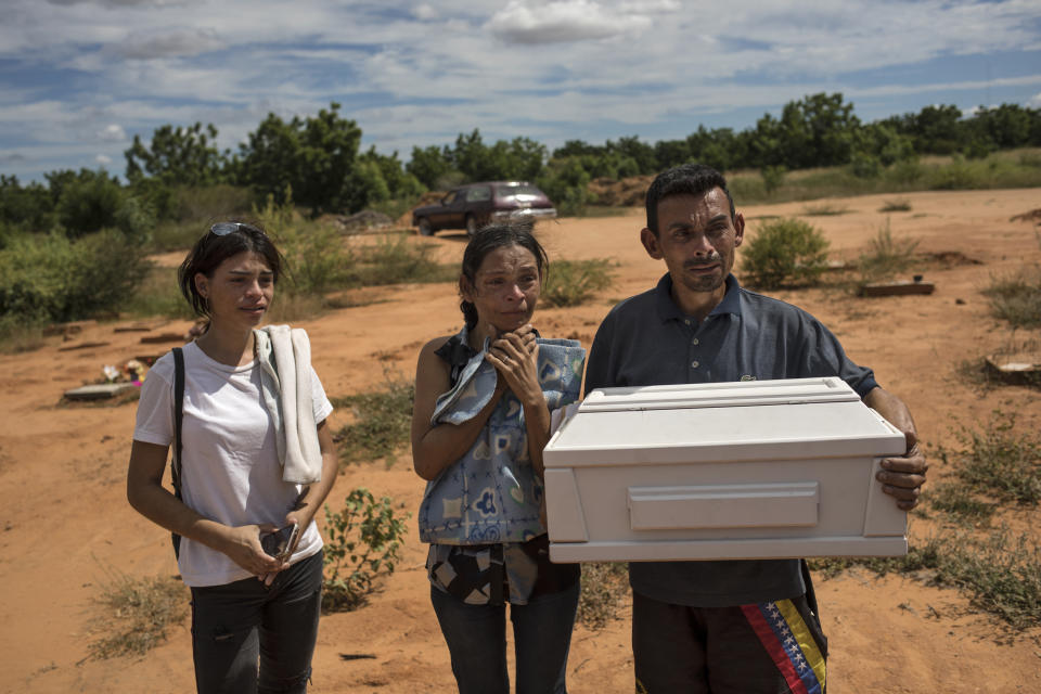 Roberto Parra carries the remains of his son Matias Alejandro alongside his wife Maria Isabel Parra and daughter Alejandra Parra at San Sebastian municipality cemetery before burying him in Maracaibo, Venezuela, Nov. 27, 2019. Parra said his 19-day-old boy died after he was born with lung problems at a public hospital, where, after his wife was turned away from the first hospital, was left to deliver alone in a dirty chair before doctors rushed her up the stairs with her baby's head already exposed. Although the baby was born with respiratory problems, they were told to take him home because he could get sicker if they stayed. (AP Photo/Rodrigo Abd)