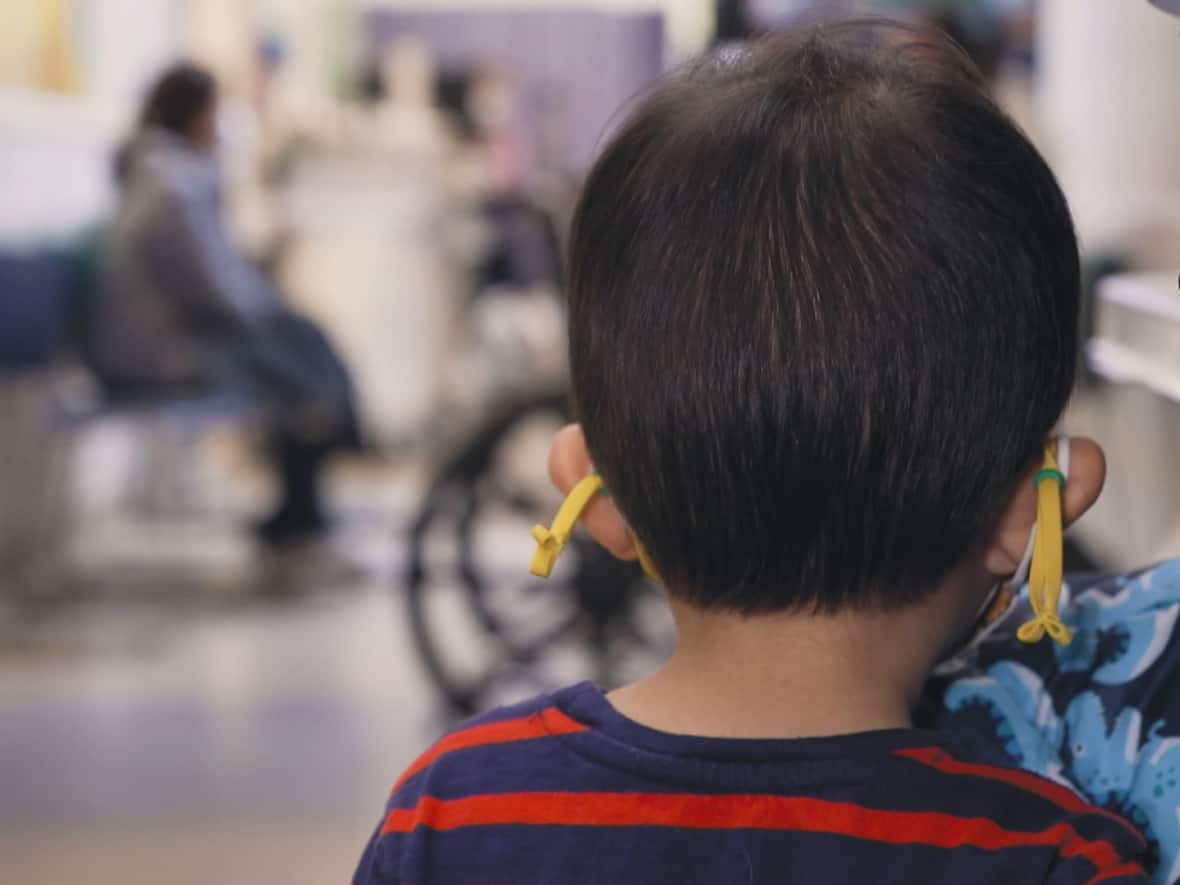 A child waits in the emergency department of the Hospital for Sick Children in Toronto, amid a fall surge in childhood respiratory viruses. Some patients are waiting up to 12 hours, according to data obtained from SickKids. (Turgut Yeter/CBC - image credit)