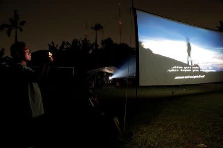 A man takes a picture whilst watching a film at a wedding party in Tangerang, Indonesia, April 15, 2017. REUTERS/Beawiharta/Files