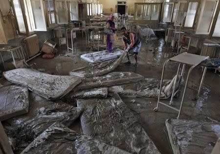 A man removes muddied beddings from a hospital ward which was damaged by flooding in Srinagar September 21, 2014. REUTERS/Danish Ismail