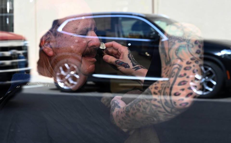 Brandy Fogg trims a customer’s mustache as seen through the window at the Oxford Barbershop in downtown Bradenton.