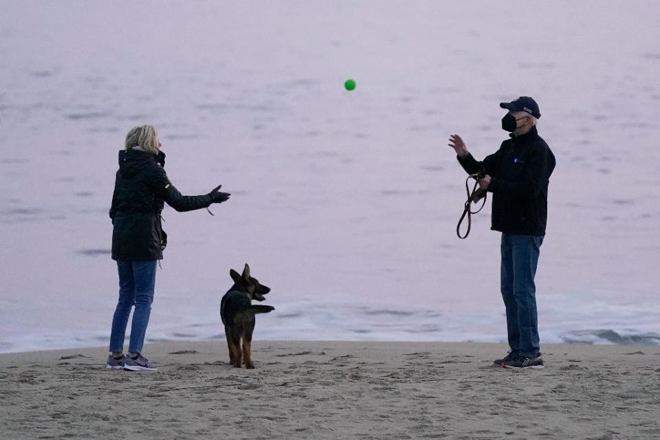 First lady Jill Biden tosses a ball to President Joe Biden as they take their dog Commander for a walk in Rehoboth Beach, Del., on Dec. 28, 2021. - Credit: AP