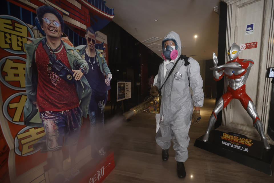 Volunteers with the Blue Sky Rescue team perform disinfecting of a cinema before it reopens for business in Beijing Friday, July 24, 2020. Theaters in China, the world's second largest movie market, this week reopened from the coronavirus shut down with theaters limited to 30% capacity. (AP Photo/Ng Han Guan)