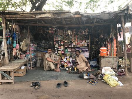 Men sit at a cobbler shop at a market in the town of Rabwah, Pakistan July 9, 2018. Picture taken July 9, 2018. REUTERS/Saad Sayeed