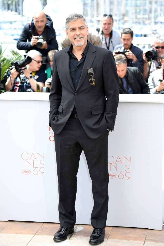 George Clooney porte un costume gris et une chemise bleu marine