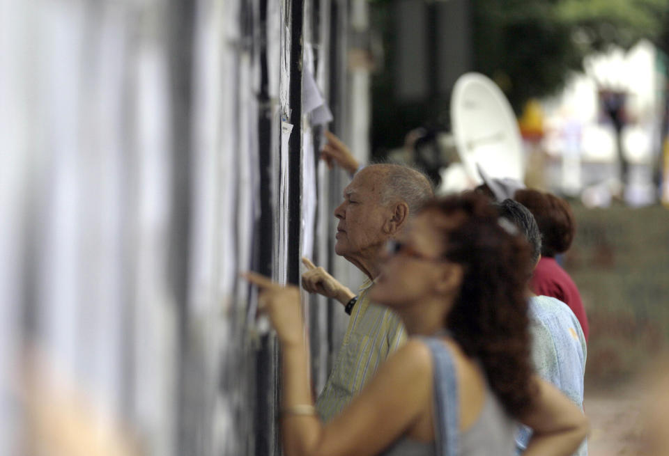 People check a voters' register during a mock election to simulate upcoming Oct. 7 presidential election at a polling station in Caracas, Venezuela, Sunday, Aug. 5, 2012. The country's electoral council has long used fingerprint scanners at the entrance to polling places to ensure voter identification. But this year, the readers will be hooked to the electronic voting machines themselves. Citizens must press down a thumb to activate the ballot system. (AP Photo/Fernando Llano)
