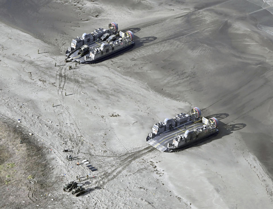 This aerial photo shows heavy equipment, left bottom, being unloaded from landing crafts of Japanese Self Defense Force in the earthquake-hit city, Wajima, Ishikawa prefecture, Japan Wednesday, Jan. 3, 2024. (Kyodo News via AP)