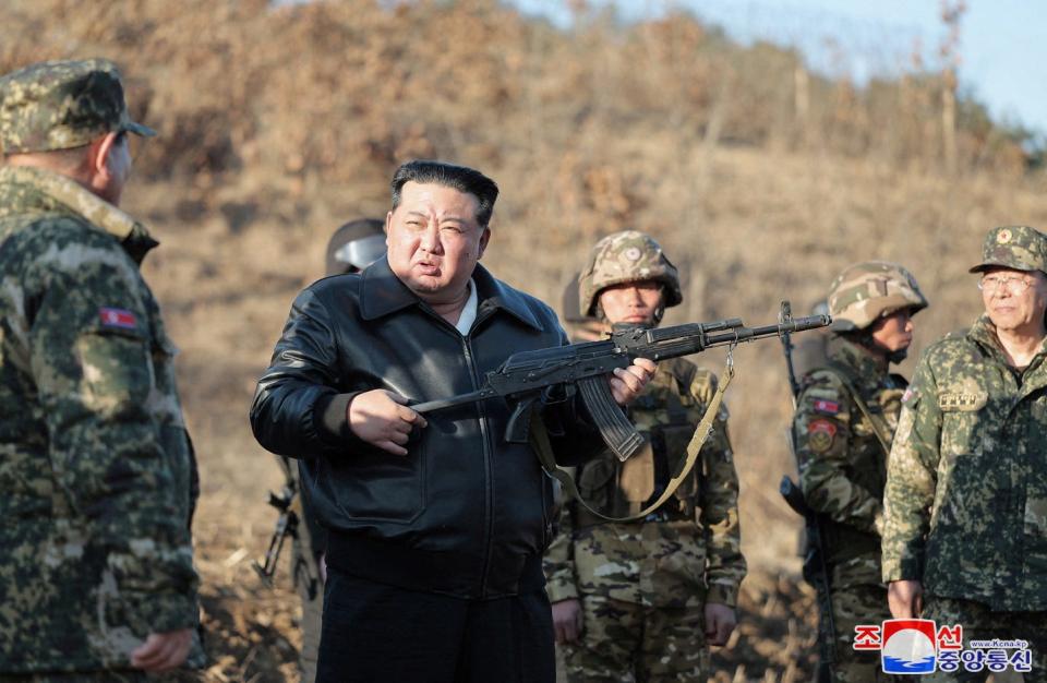 North Korean leader Kim Jong Un holds a firearm surrounded by military personnel