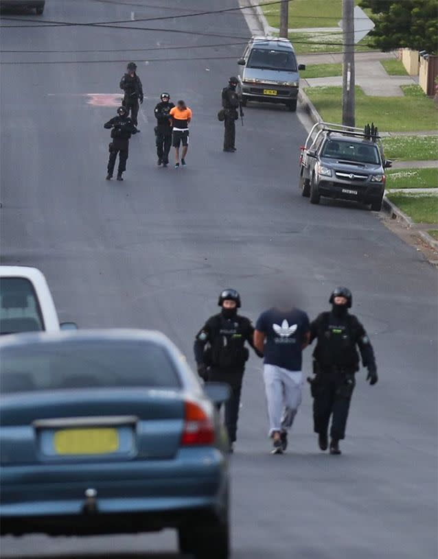 A man is taken into custody during joint NSW police and AFP raids on homes in Sydney's west this morning. Photo: NSW Police