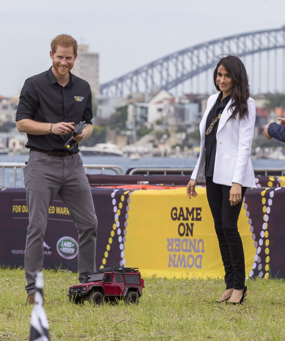 Britain's Prince Harry, left, and his wife Meghan, the Duchess of Sussex are seen playing with remote control cars during the Jaguar Land Rover Driving Challenge on Day 1 of the Invictus Games on Cockatoo Island in Sydney, Australia, Saturday, Oct. 20, 2018. (Craig Golding/AAP Image via AP)