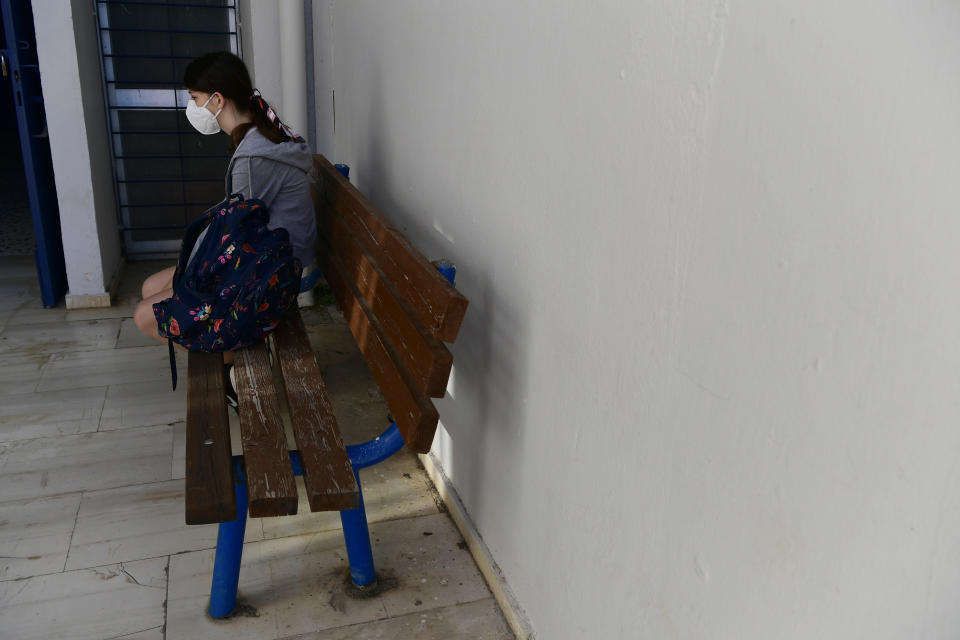 A student wearing a face mask to help curb the spread of the coronavirus, sits on a bench at a junior high school in Athens, Monday, May 10, 2021. More than 1.1 million pupils and 127,300 teachers returned to school on Monday as primary and junior high school reopened its doors with mandatory home self-tests. (AP Photo/Michael Varaklas)