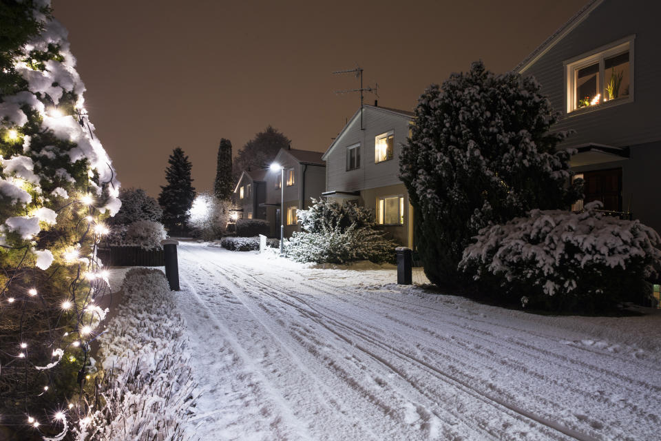 Houses by snow covered road during Christmas at night
