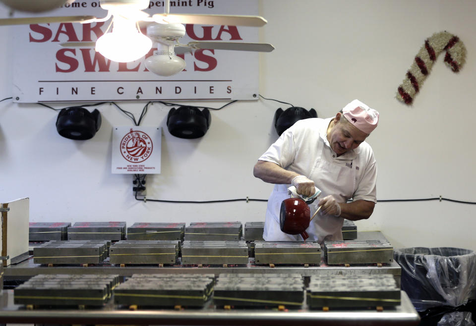 In this Dec. 6, 2012, photo, Mike Fitzgerald pours hot peppermint mixture into a mold while making peppermint pigs at his Saratoga Sweets store in Halfmoon, N.Y. A holiday tradition in upstate New York has a peppermint twist: pig-shaped hard candies are sold with little metal hammers to be smashed at Christmas. (AP Photo/Mike Groll)