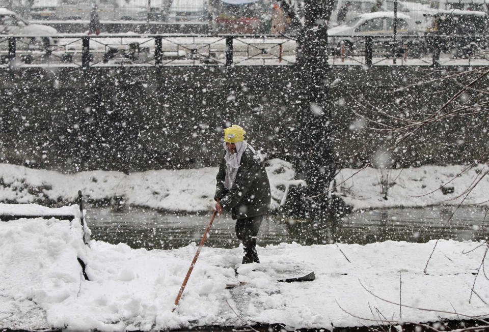 A Kashmiri boatman removes snow from his boat at the Dal Lake in Srinagar, India, Tuesday, March 11, 2014. The Kashmir valley was Tuesday cut off from rest of India due to heavy snowfall. (AP Photo/Mukhtar Khan)