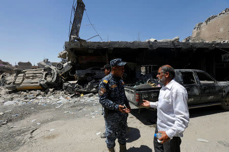 A member of Iraqi federal police talks to a man in the destroyed Old City of Mosul, Iraq August 7, 2017. REUTERS/Suhaib Salem