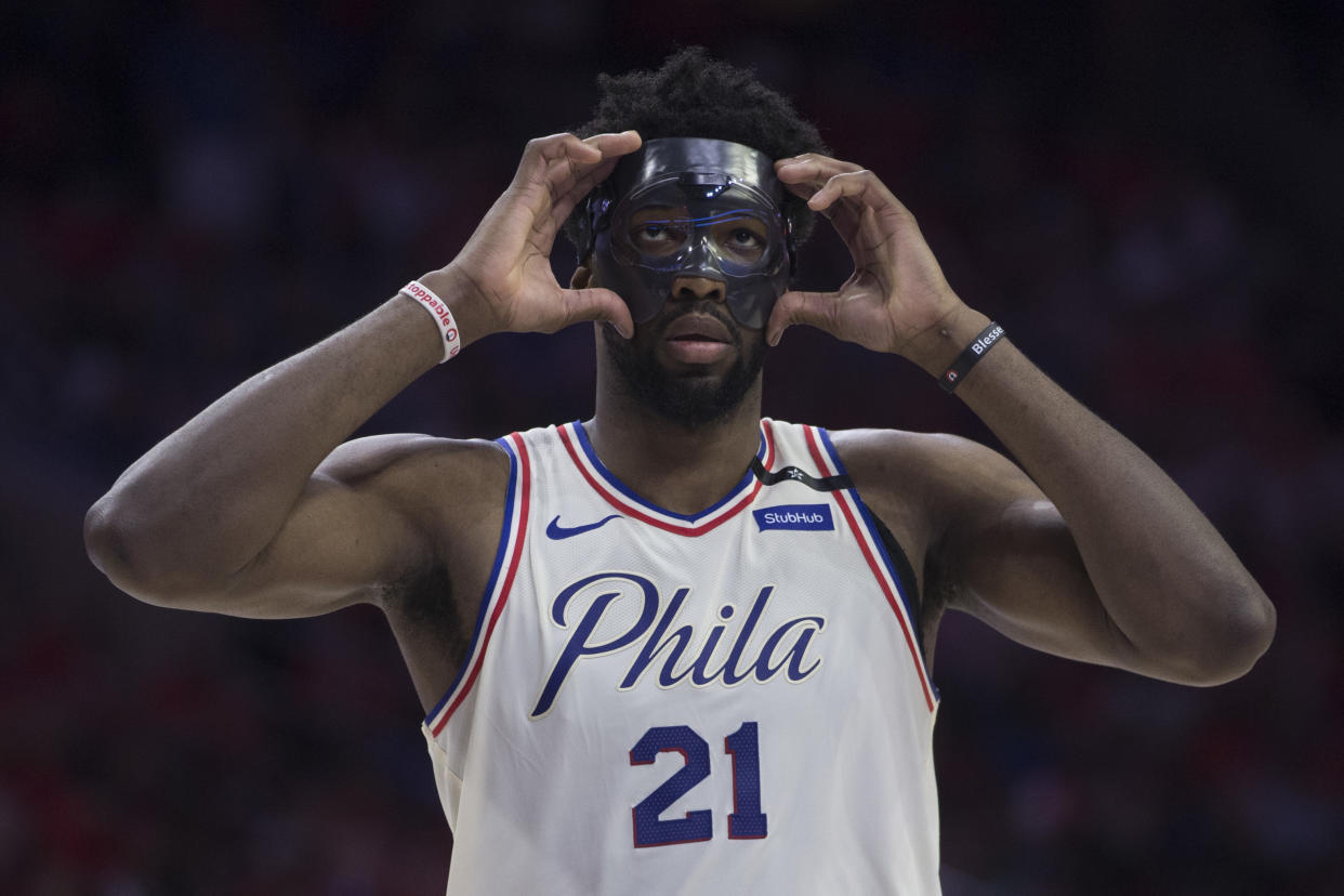 Philadelphia 76ers center Joel Embiid adjusts his mask against the Boston Celtics in the second round of the 2018 NBA playoffs. (Photo by Mitchell Leff/Getty Images)