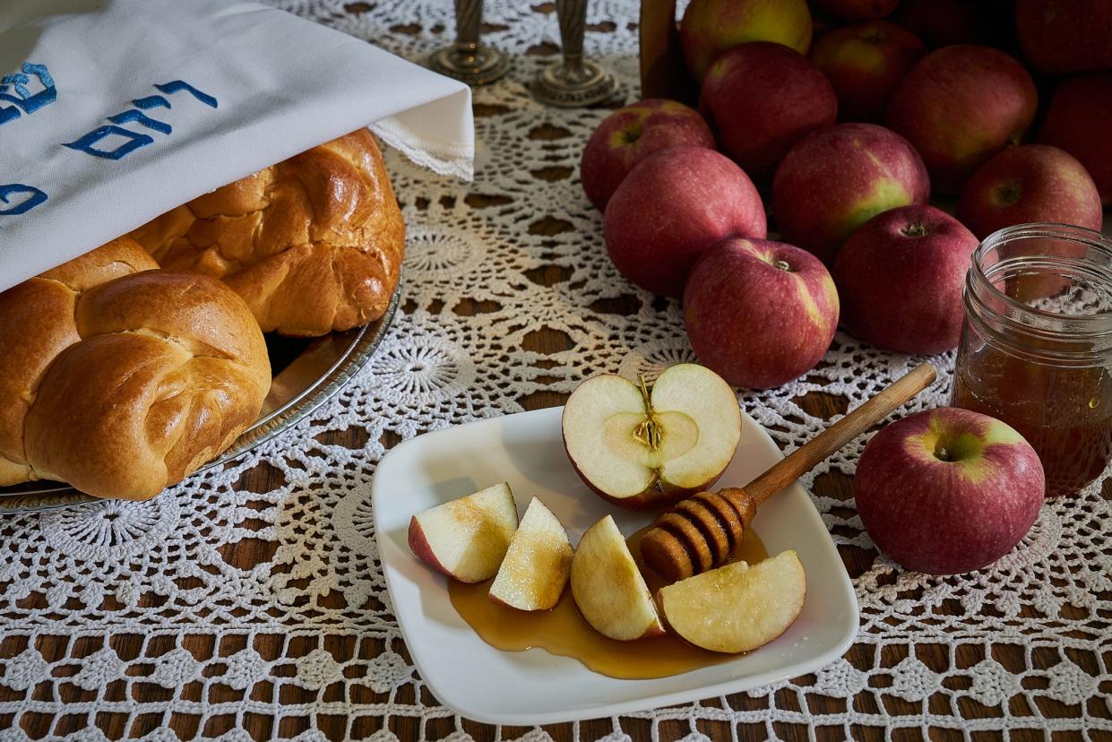 A Rosh Hashana holiday table with apples, honey and challah.