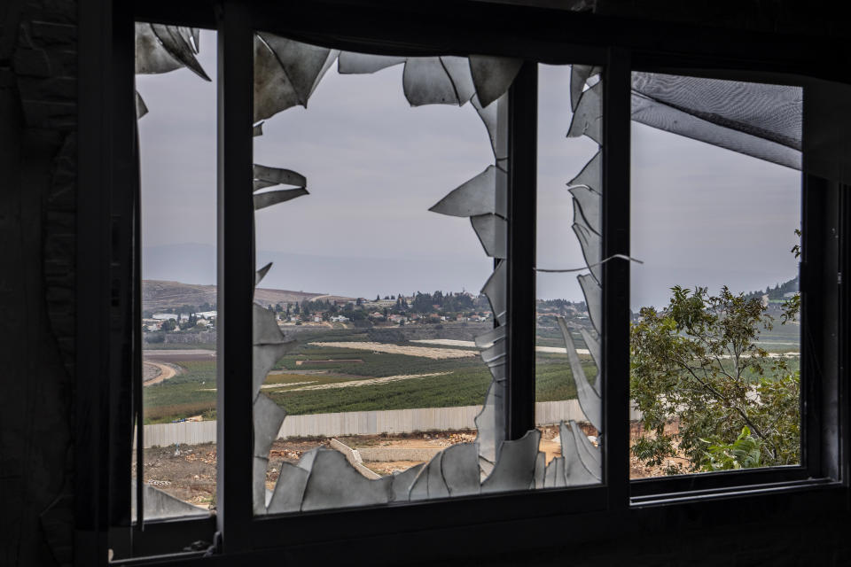 The Israeli town of Metula, background, is seen through a broken window of a house that hit by Israeli shelling in Kfar Kila border village with Israel, south Lebanon, Saturday, Nov. 25, 2023. With a cautious calm prevailing over the border area in south Lebanon Saturday, the second day of a four-day cease-fire between Hamas and Israel, villages that had emptied of their residents came back to life at least briefly. (AP Photo/Hassan Ammar)