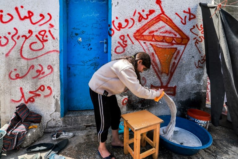 A girl washes clothes by hand at a camp for displaced Palestinians erected in a school run by the United Nations Relief and Works Agency for Palestine Refugees (UNRWA) in Rafah in the southern Gaza Strip on March 13, 2024 (MOHAMMED ABED)