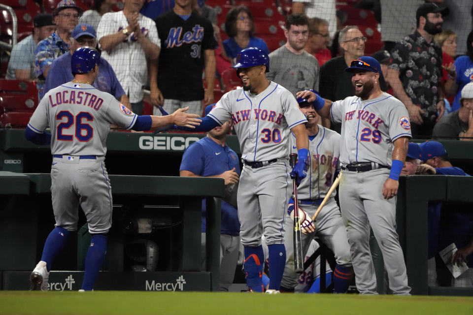 New York Mets' Tim Locastro (26) is congratulated by teammates Rafael Ortega (30) and DJ Stewart (29) after hitting a solo home run during the ninth inning of a baseball game against the St. Louis Cardinals Thursday, Aug. 17, 2023, in St. Louis. (AP Photo/Jeff Roberson)