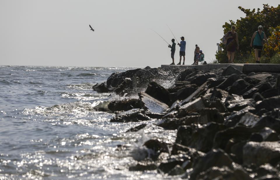 Fisherman are seen along the jetty at John's Pass Thursday, Feb. 23, 2023 in Madeira Beach, Fla. Florida's southwest coast experienced a flare-up of the toxic red tide algae this week, setting off concerns that it could continue to stick around for a while. The current bloom started in October. (Chris Urso/Tampa Bay Times via AP)