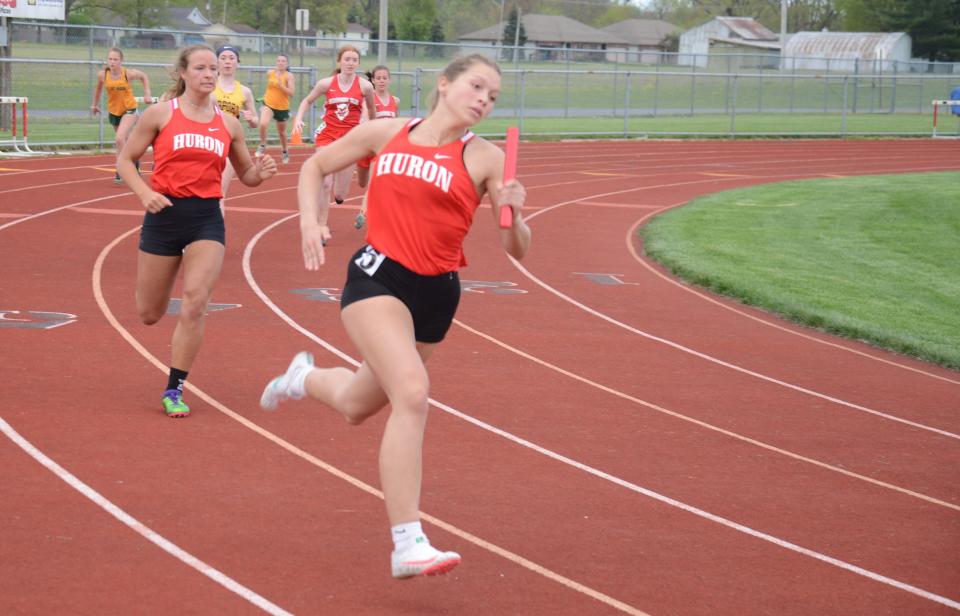 Chloe Evans of New Boston Huron heads toward the finish after taking the baton from teammate Kelsey Trombly in the 400-meter relay earlier this season.