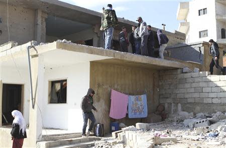 People inspect a site hit by rocket fire from Syria at the Lebanese border town of Arsal January 17, 2014. REUTERS/Ahmad Shalha