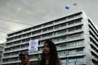 People walk past the finance ministry building in Athens on July 1, 2015, where employees hung a banner reading "NO to blackmail and austerity"