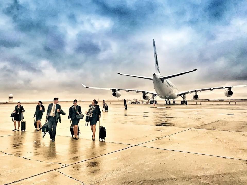 AirX Charters' A340 aircraft with flight attendants and pilot walking away.