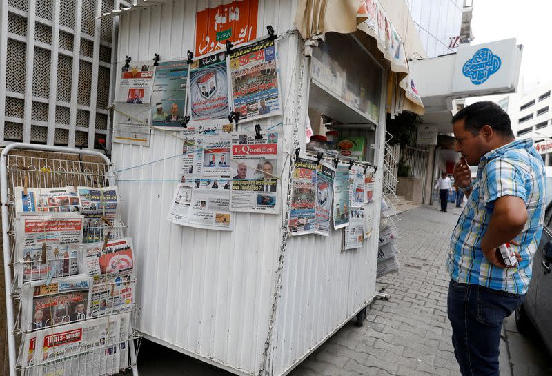 FILE PHOTO: A man looks at local newspapers displaying pictures of two candidates for the second round of Tunisia's presidential election, in Tunis