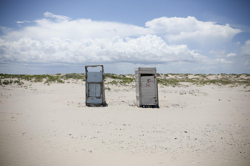 In this Aug. 3, 2019 photo, two public restrooms dot the landscape on Playa Bagdad near the border city of Matamoros, Mexico. The last thing the drug cartels want, is to draw U.S. patrols to the area, which is already hard to reach by any normal route. It is precisely that remoteness and lack of patrols that serves the drug trade, the economic activity that has become the mainstay here. (AP Photo/Emilio Espejel)