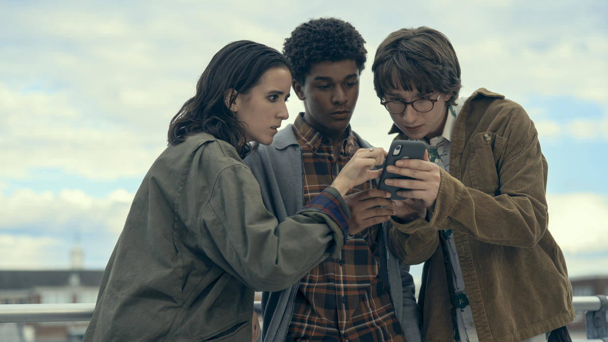  Ema, Mickey, and Arthur stare at a mobile phone in Harlan Coben's Shelter. 