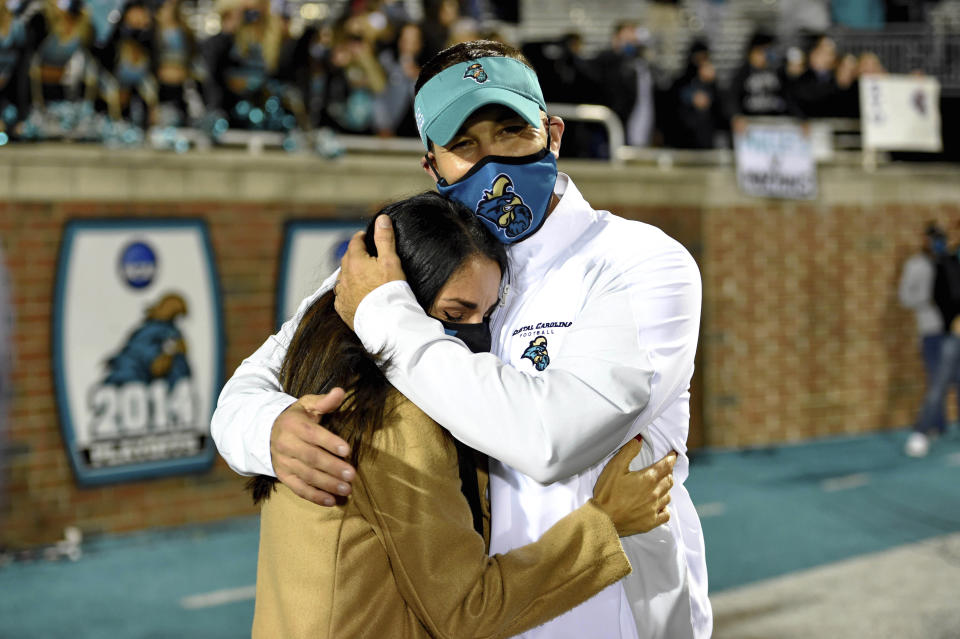 FILE - In this Dec. 5, 2020, file photo, Coastal Carolina coach Jamey Chadwell hugs his wife, Solmaz, after the team's NCAA college football game against BYU in Conway, S.C. Chadwell is The Associated Press college football coach of the year after leading the Chanticleers to a surprising near-perfect season. Chadwell received 16 first-place votes and 88 points from the AP Top 25 panel to finish ahead of Indiana’s Tom Allen, who was second with 14 first-place votes and 66 points. (AP Photo/Richard Shiro, File)