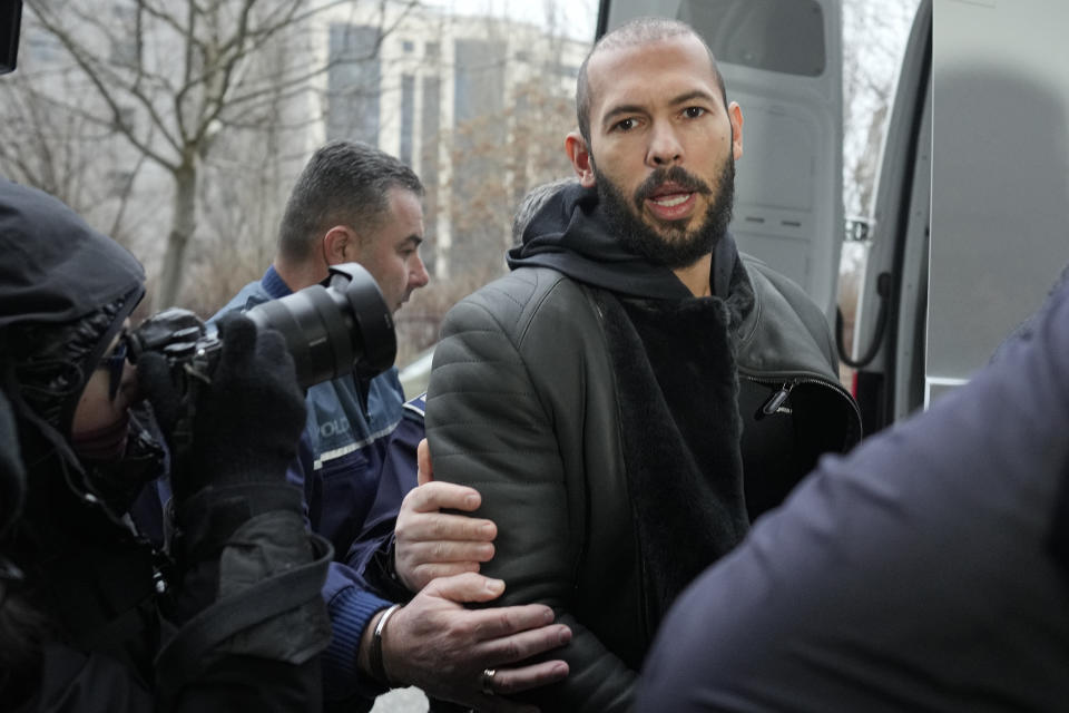 Police officers escort Andrew Tate, handcuffed to his brother Tristan, outside the Directorate for Investigating Organized Crime and Terrorism (DIICOT) where prosecutors examine electronic equipment confiscated during the investigation in their case, in Bucharest, Romania, Thursday, Jan. 26, 2023. Divisive influencer Andrew Tate and his brother Tristan, are held on charges of being part of an organized crime group, human trafficking and rape. (AP Photo/Vadim Ghirda)