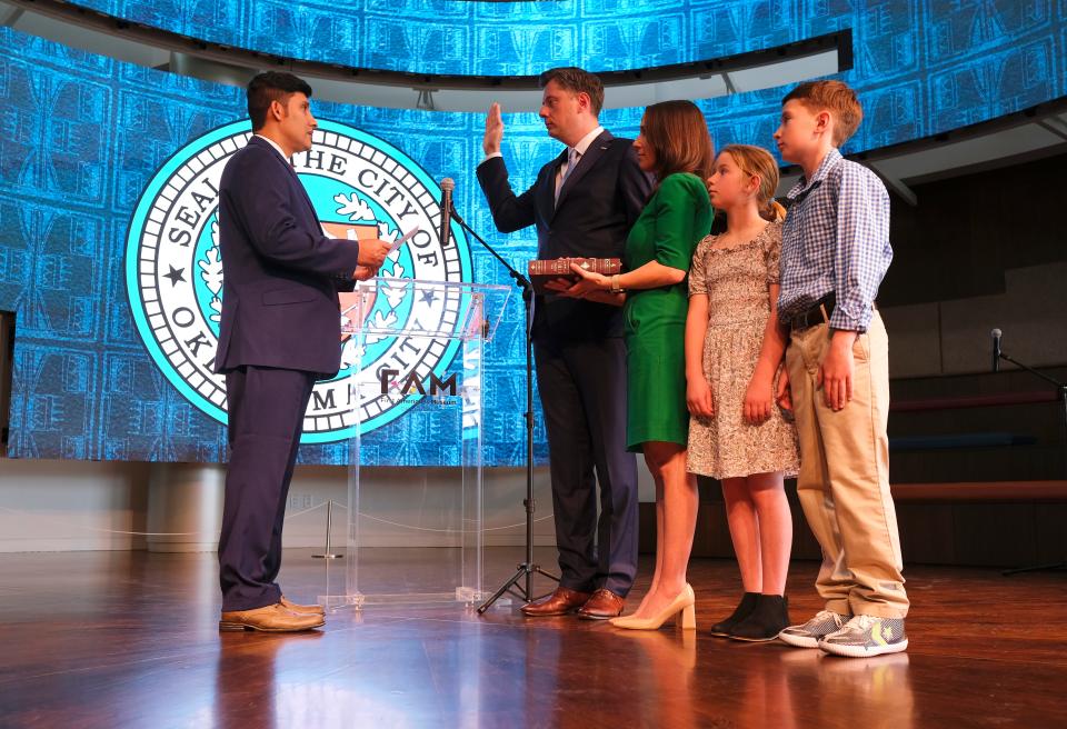 Dr. Feroz Bashari, an Afghan refugee, reads the oath of office for Mayor David Holt as his wife, Rachel, holds a Bible and his children, Maggie and George, look on during a ceremonial swearing-in at First Americans Museum.