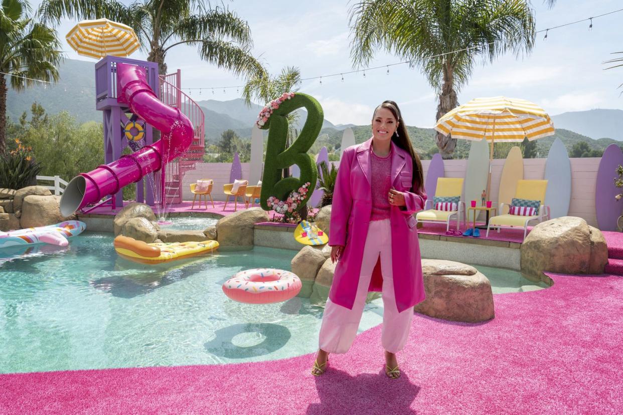 host ashley graham poses in the finished backyard, as seen on barbie dream house challenge, season 1